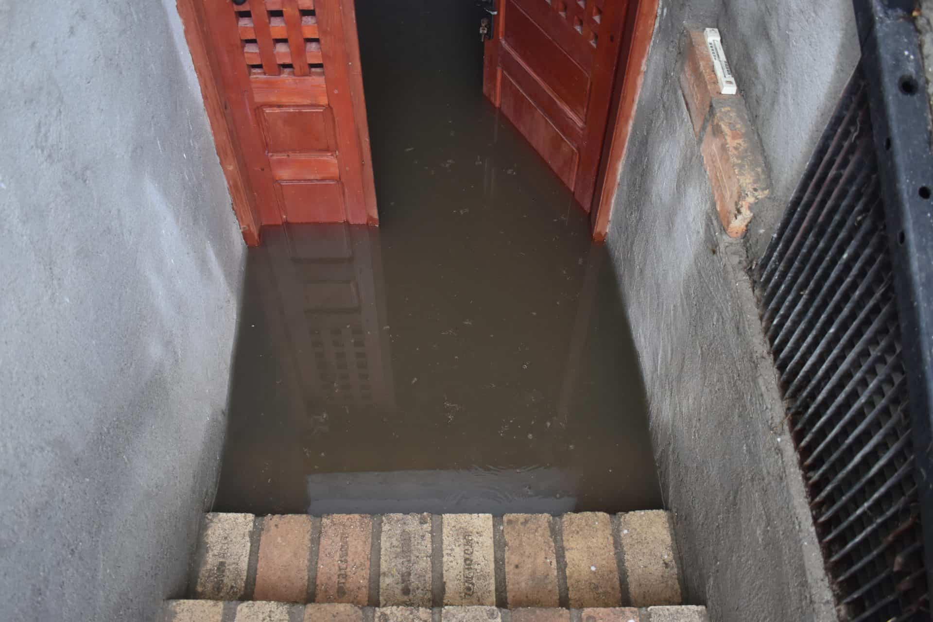 Flooded basement at the bottom of the stairs with a red door